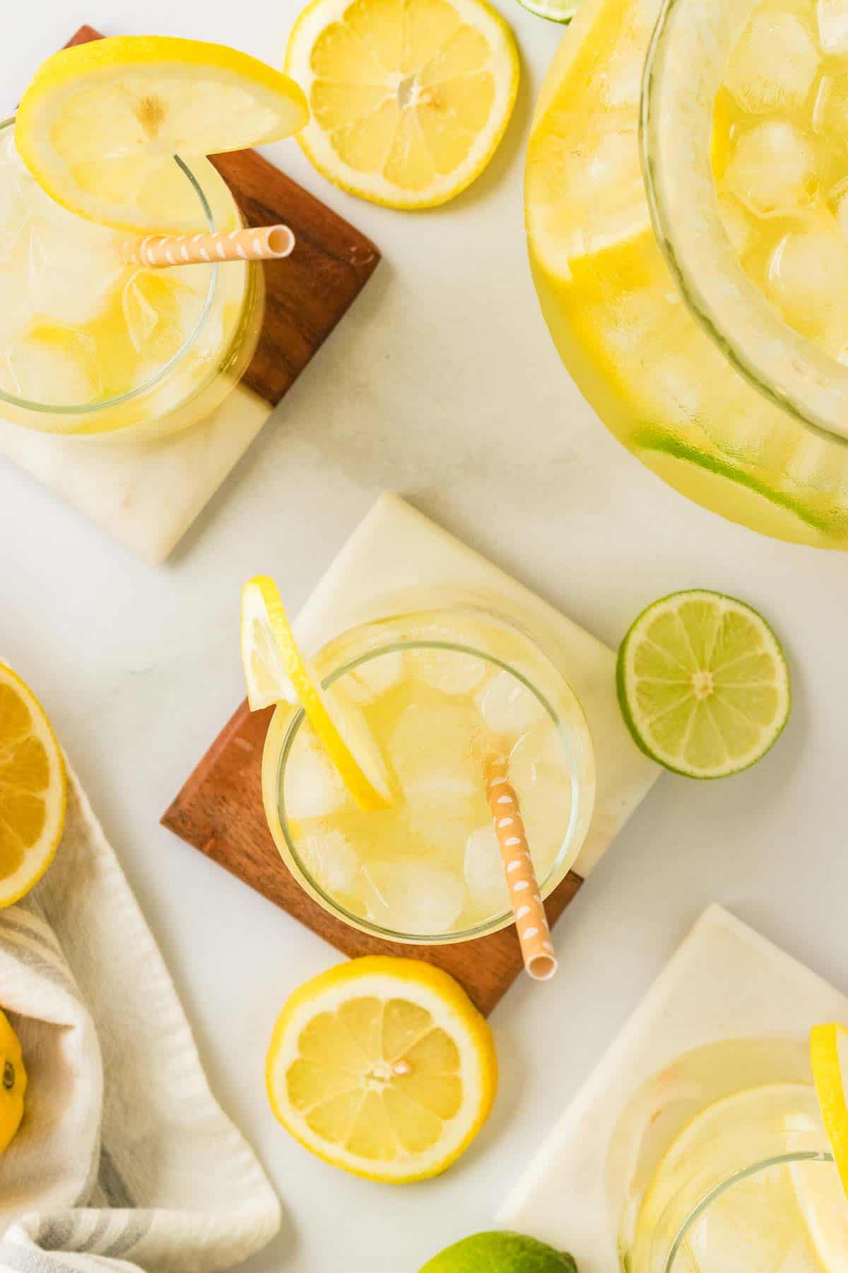 Glasses of lemon limeade surrounded by lemon and lime slices.