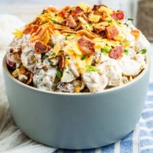 A heaping bowl of ranch potato salad on a blue and white striped napkin.