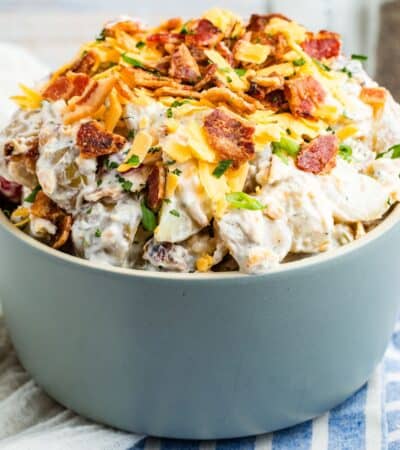 A heaping bowl of ranch potato salad on a blue and white striped napkin.