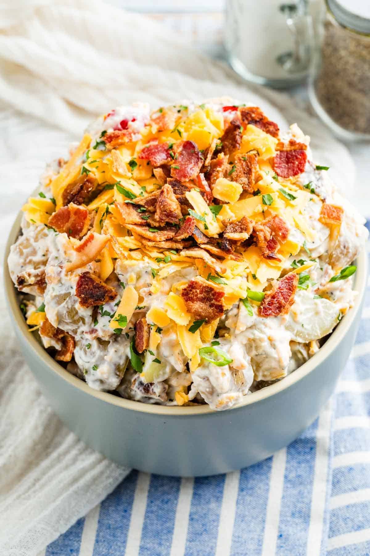 Ranch potato salad is a lightened-up version of a summer side dish made with Greek yogurt and all your favorite savory flavors. A bowl of ranch potato salad topped with bacon.