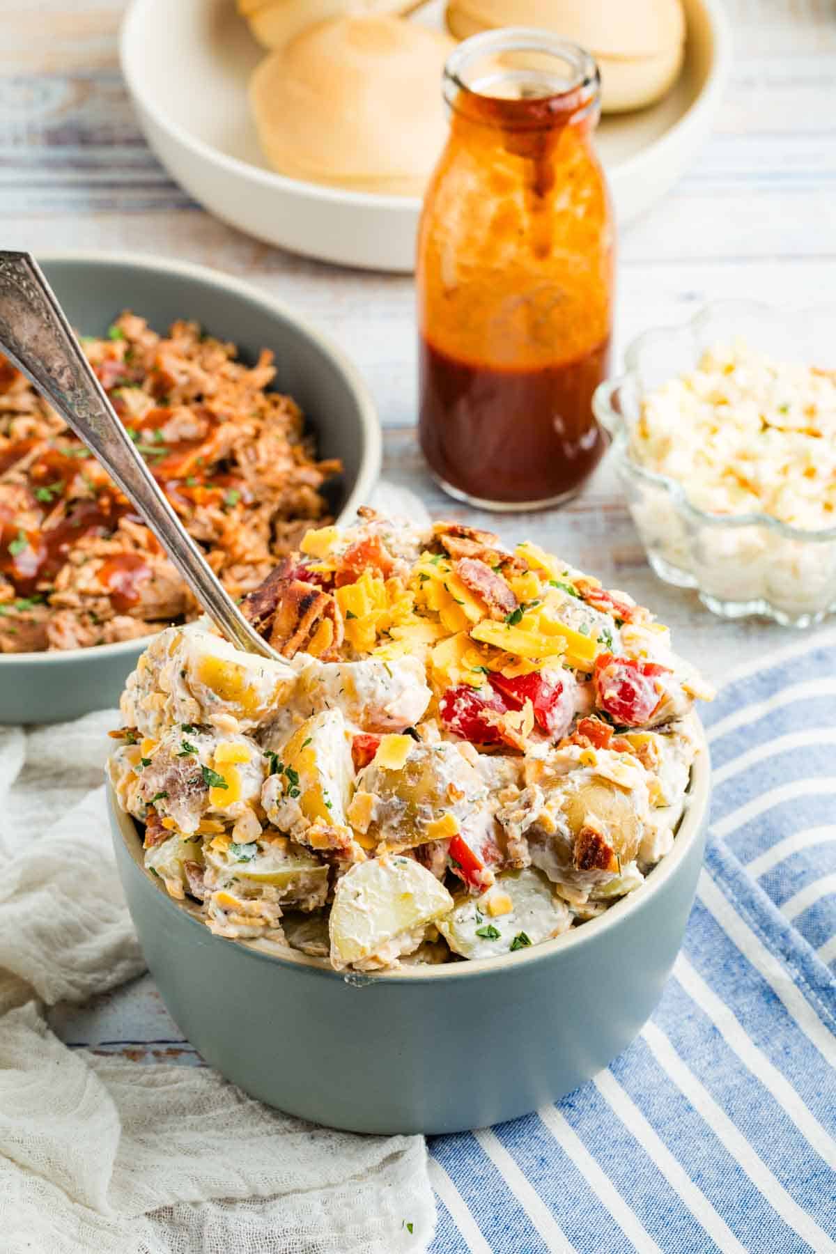 A spoon sticks out of a bowl of ranch potato salad.