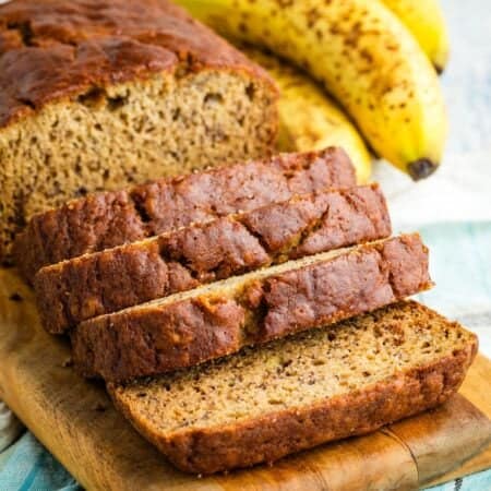 A loaf of gluten-free banana bread cut into slices on a cutting board.
