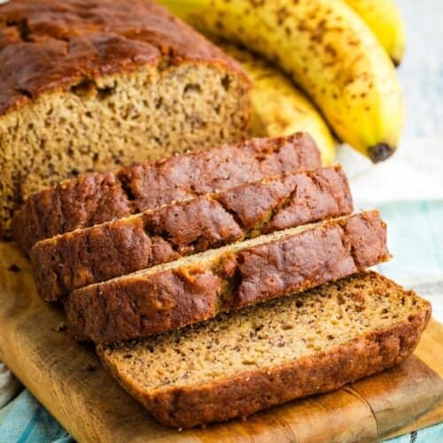 A loaf of gluten-free banana bread cut into slices on a cutting board.