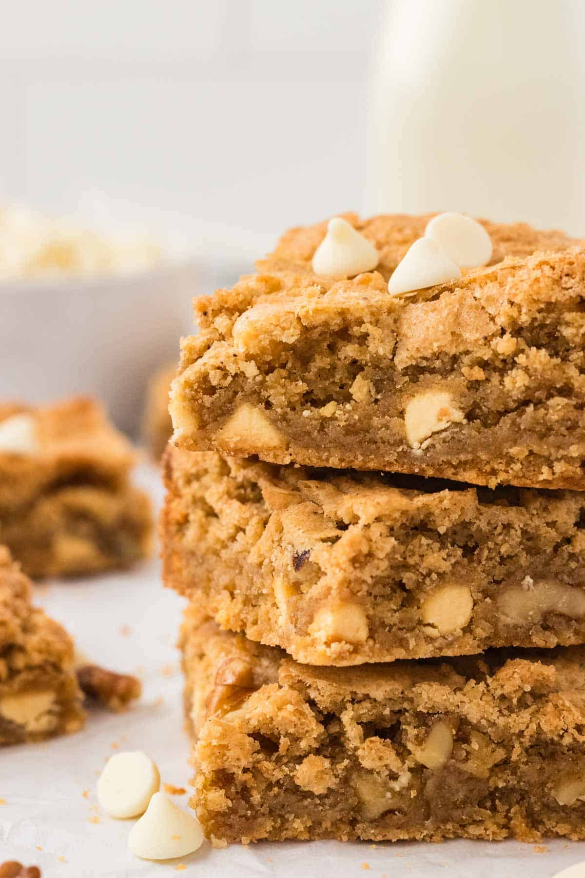 Deeply rich gluten free blondies build off a base of browned butter for a crisp-chewy treat that's studded with white chocolate and walnuts. Three gluten free blondies stacked on top of each other.