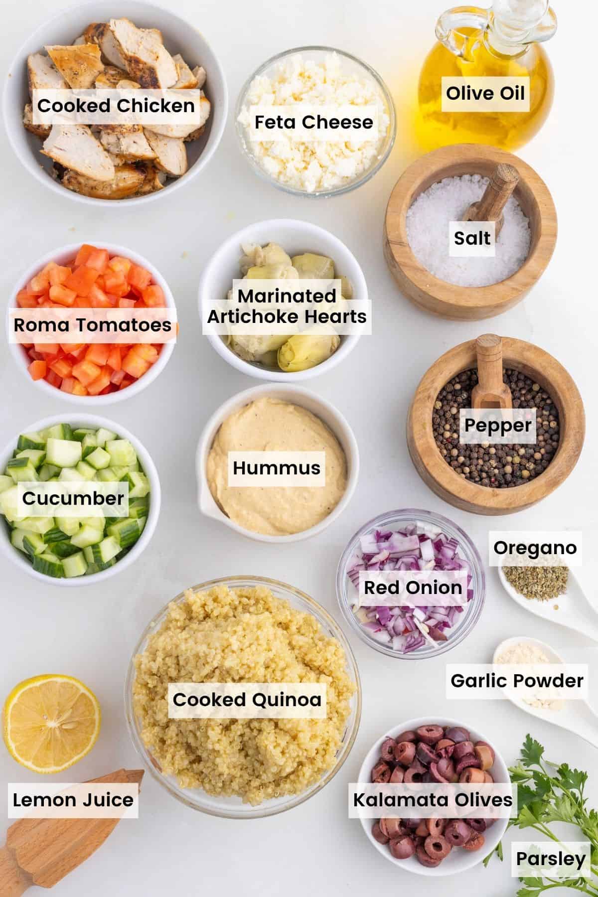 These easy Greek Chicken Bowls are loaded with fresh veggies, kalamata olives, and artichoke hearts served over quinoa and topped with hummus. Labeled ingredients for Greek chicken bowls.