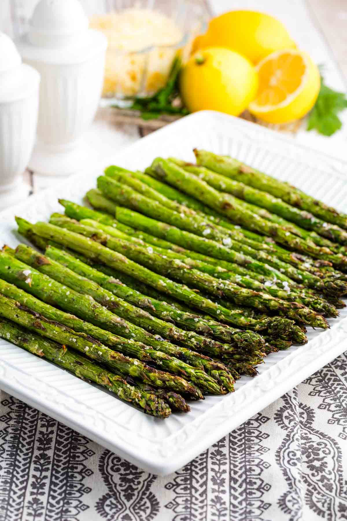 This grilled asparagus recipe produces crisp-tender asparagus cooked quickly over medium heat. A versatile vegetable side dish! Grilled asparagus is arranged on a white platter.