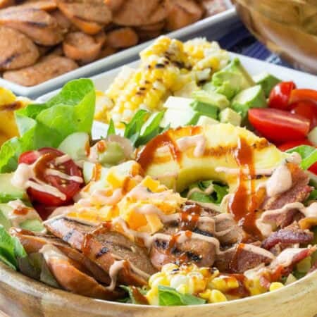 A bowl of chicken sausage salad topped with hot sauce.