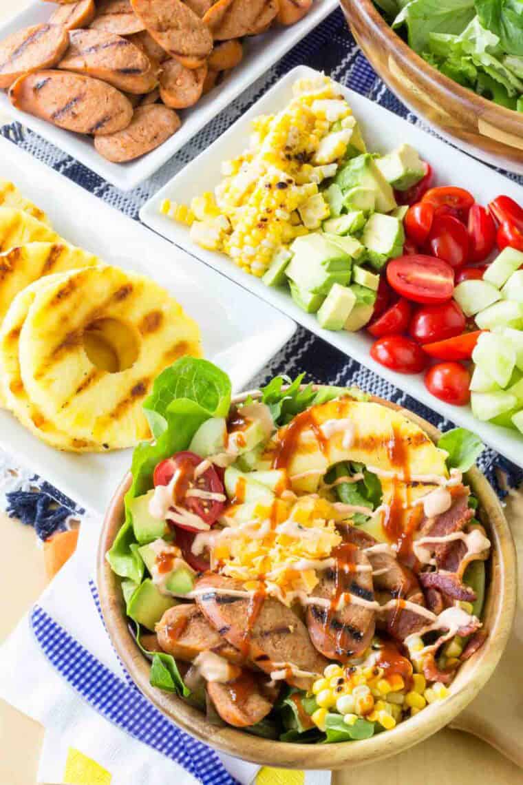 Plates of grilled pineapple and other ingredients for chicken sausage salad.