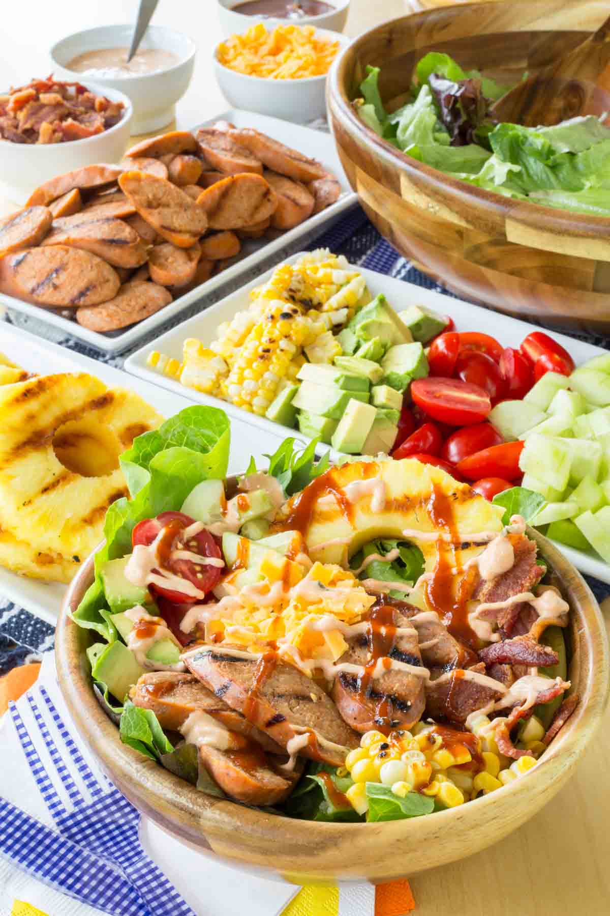 A bowl of grilled chicken sausage salad with ingredients around it.