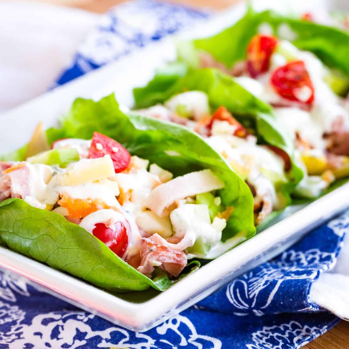A plate of ham and turkey lettuce wraps.