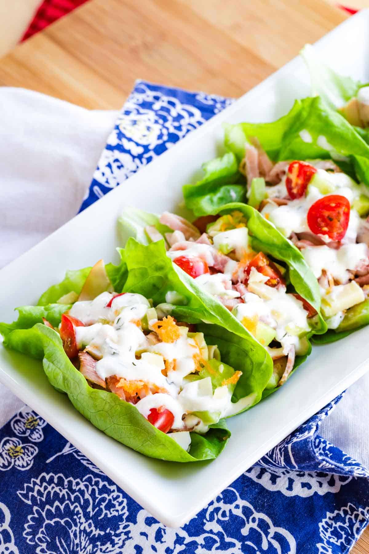 A plate of ham and turkey lettuce wraps.