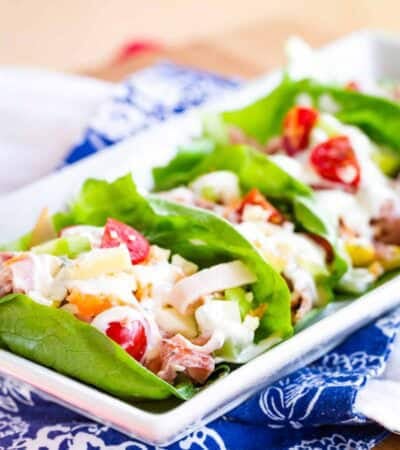 Ranch dressing is used to finish a plate of ham and turkey lettuce wraps.