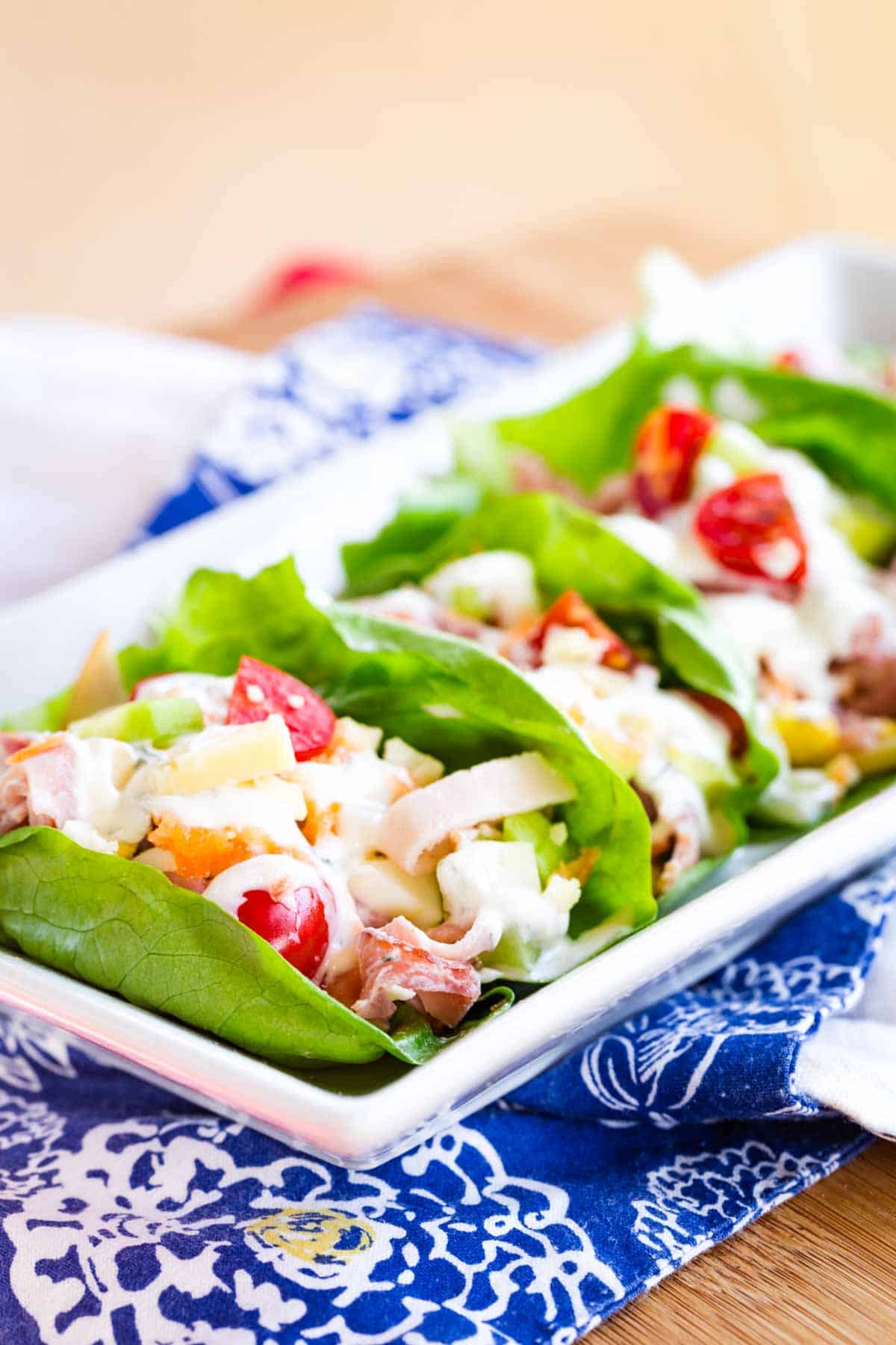 Ranch dressing is used to finish a plate of ham and turkey lettuce wraps.