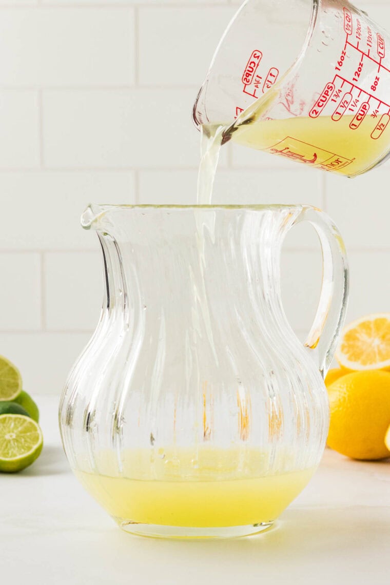 Lemon juice is poured into a pitcher.