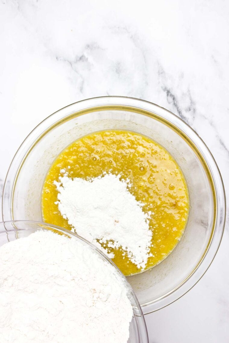 The dry mix for banana bread is added to the wet mix in a bowl.