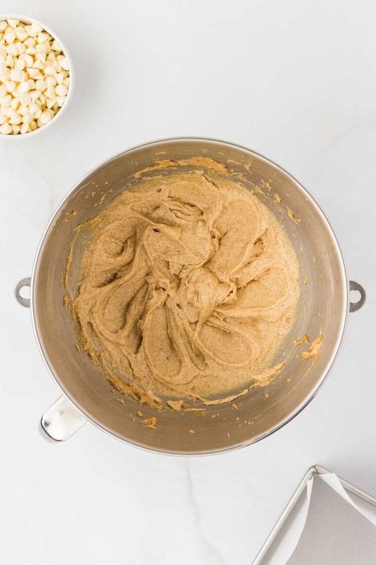 Egg is mixed into a bowl of blondie batter.