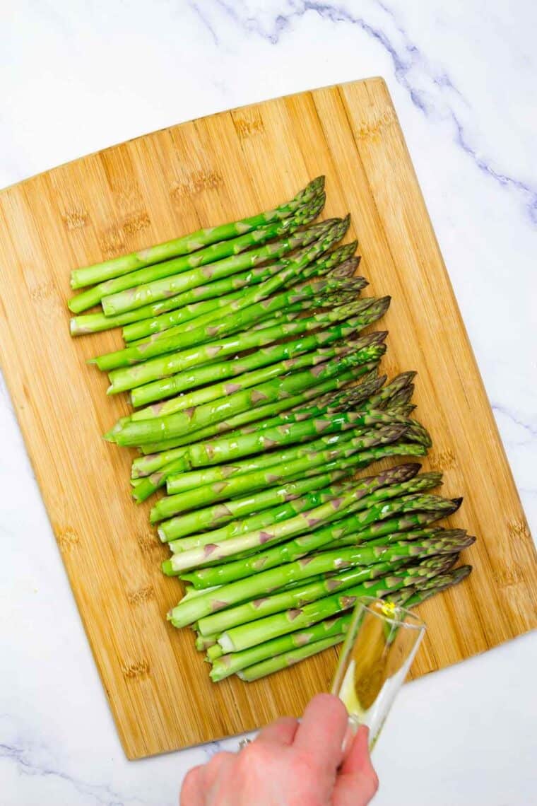 Olive oil is drizzled over asparagus.