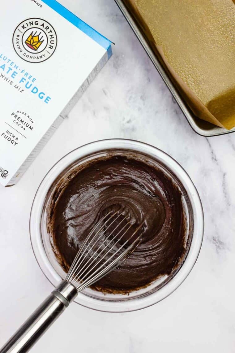 A whisk mixes brownie batter in a bowl.