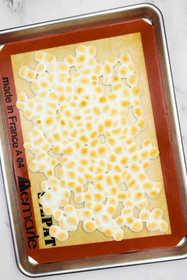 Mini marshmallows on a baking sheet after being toasted.