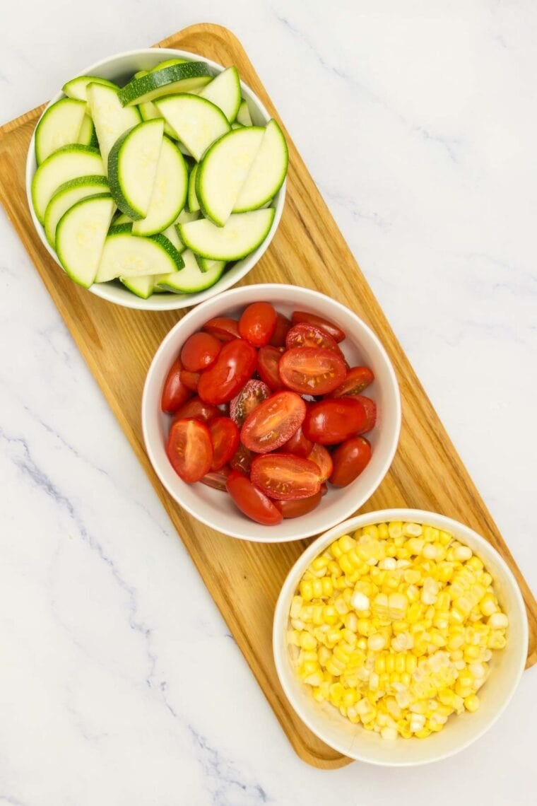 Bowls of sliced zucchini, tomatoes, and corn.