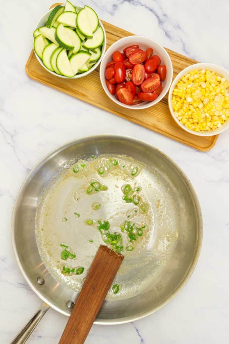 Scallions are sauteed in a pan.