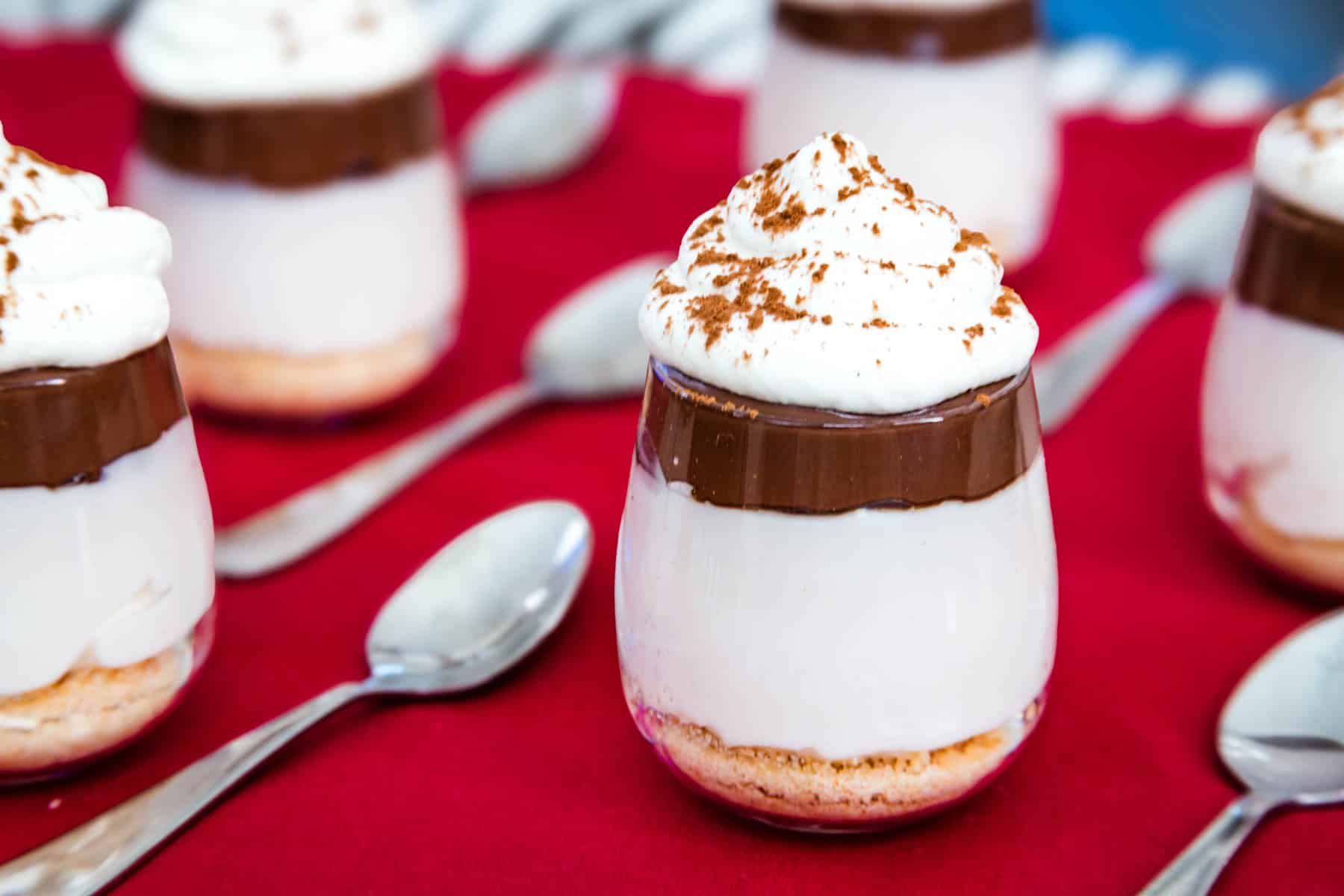 Several No-Bake Nutella Cheesecake Cups on a red napkin with mini spoons next to each one.