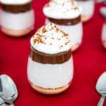 A few mini cheesecake parfaits with a Nutella layer and whipped cream on top.