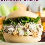A chicken salad sandwich on a roll with text overlay that says "Pecan Chicken Salad".