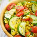 A big wooden bowl holds freshly sauteed summer vegetables.