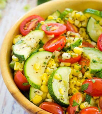 A big wooden bowl holds freshly sauteed summer vegetables.