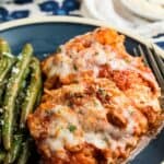 Spaghetti squash with sauce, meat, and mozzarella cheese on a plate with green beans with text overlay that says "Spaghetti Squash Lasagna".