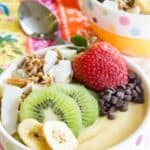 A smoothie bowl topped with fruit, chocolate chips, and granola with text overlay that says "Tropical Smoothie Bowls".