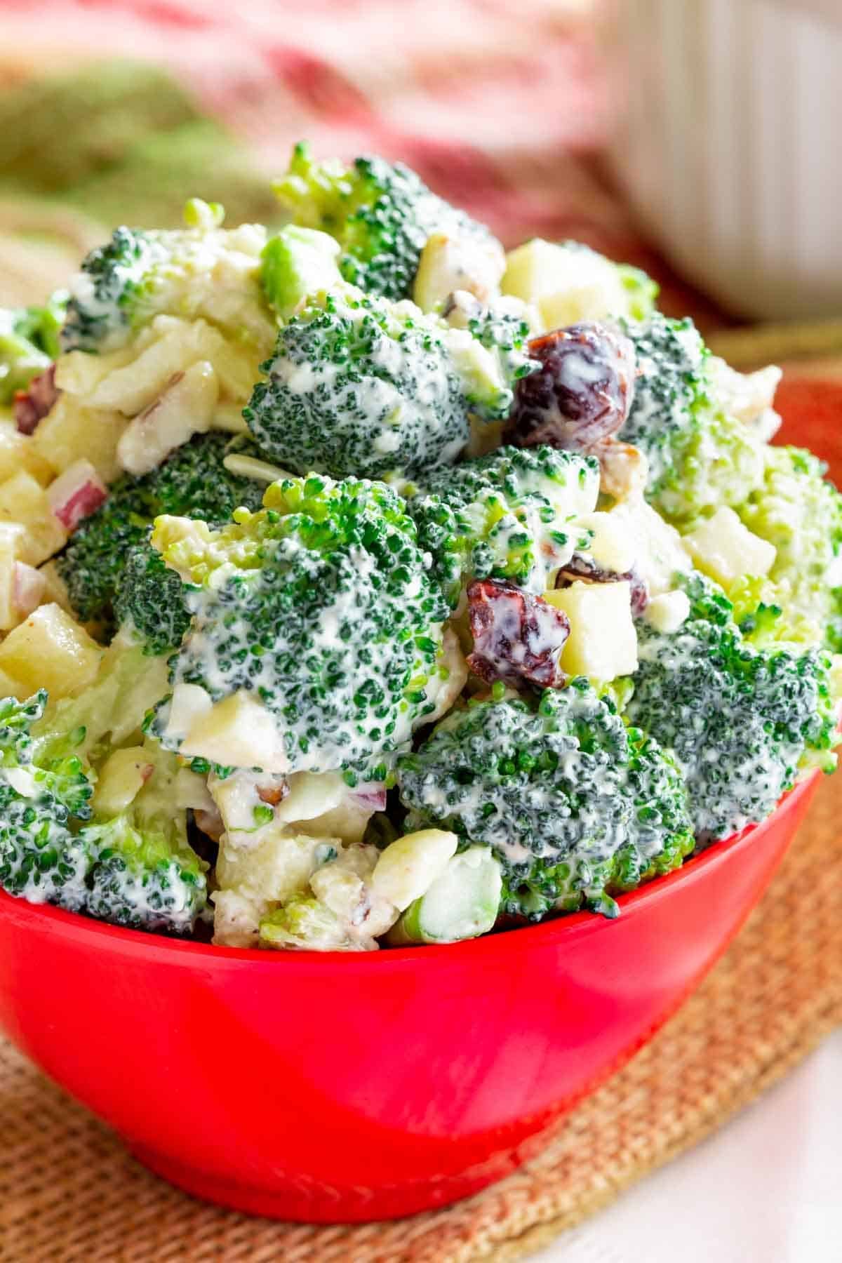 Close-up of broccoli apple salad in a red bowl.