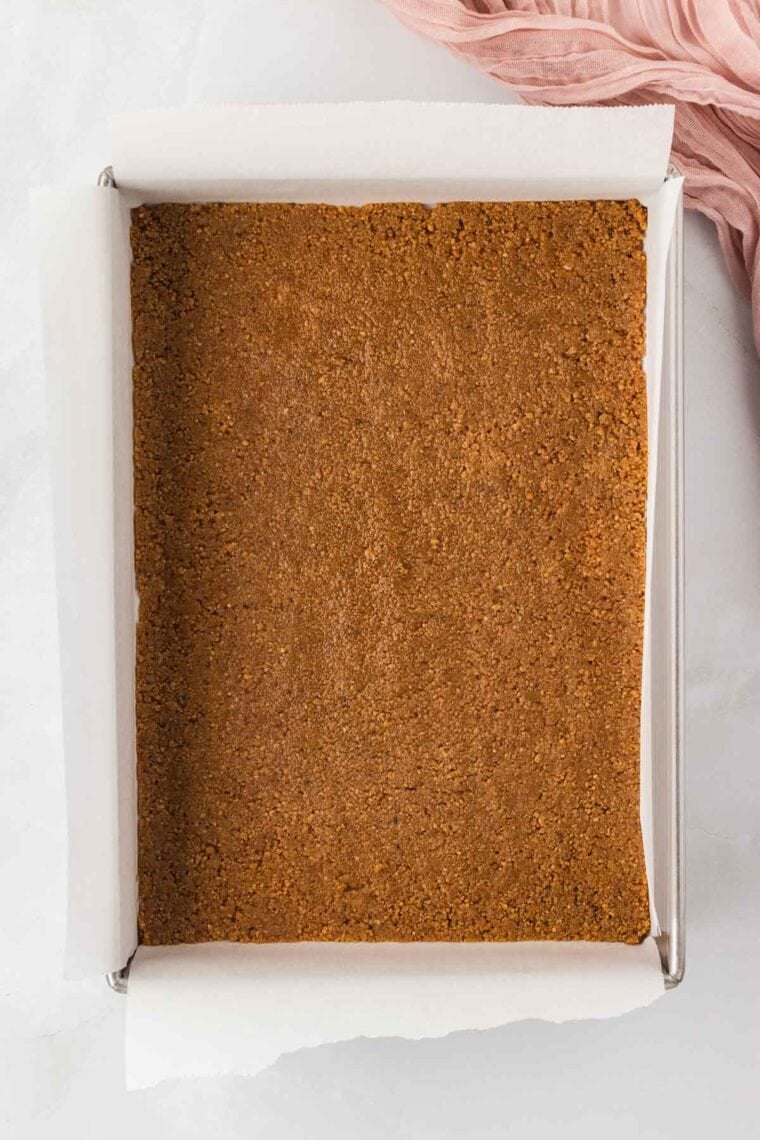 Graham cracker crust pressed into the bottom of a baking pan lined with parchment paper.