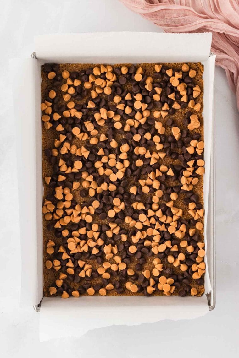 Scattering chocolate and butterscotch chips over graham cracker crust.