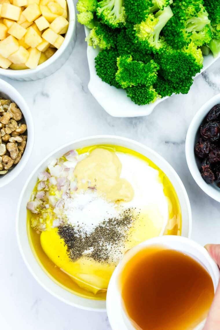 Combining Greek yogurt, apple cider vinegar, honey, olive oil, Dijon mustard, shallot, salt, and pepper in a bowl,