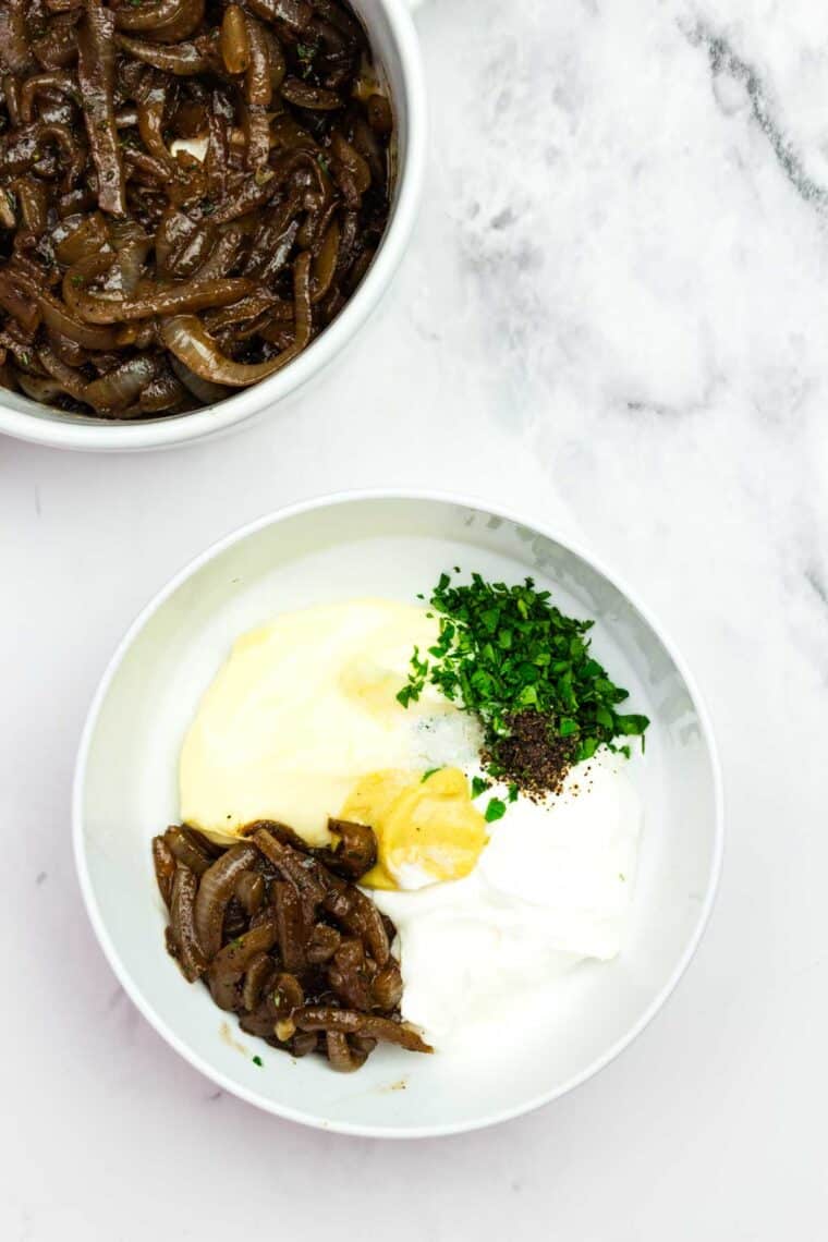 Adding ingredients for French onion spread to a bowl.