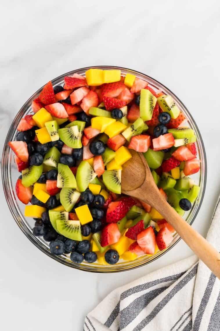 Tossing blueberries, mangos, kiwi, and strawberries with honey-lime dressing.