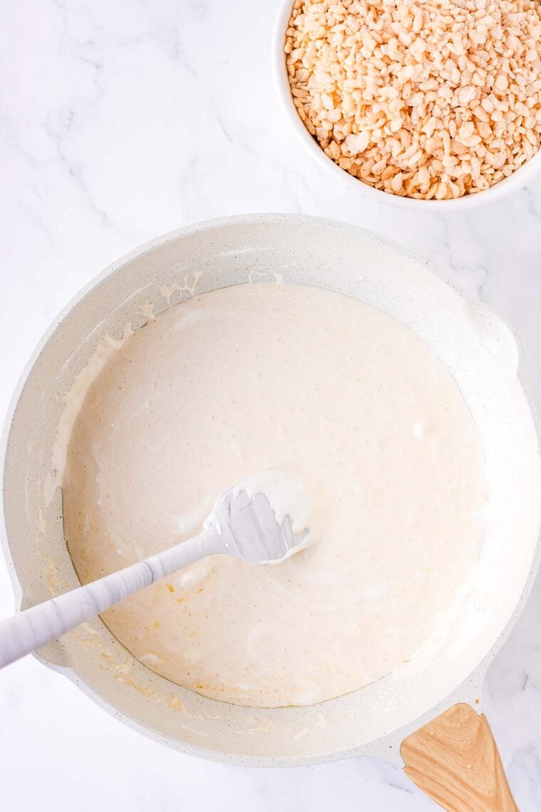 Stirring vanilla into melted marshmallow fluff and butter in a Dutch oven.