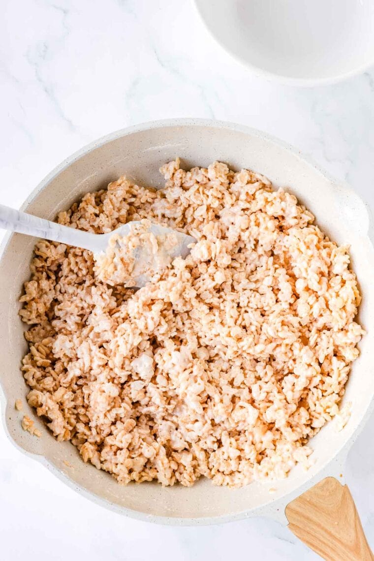 Folding crispy rice cereal into melted butter and marshmallow fluff.