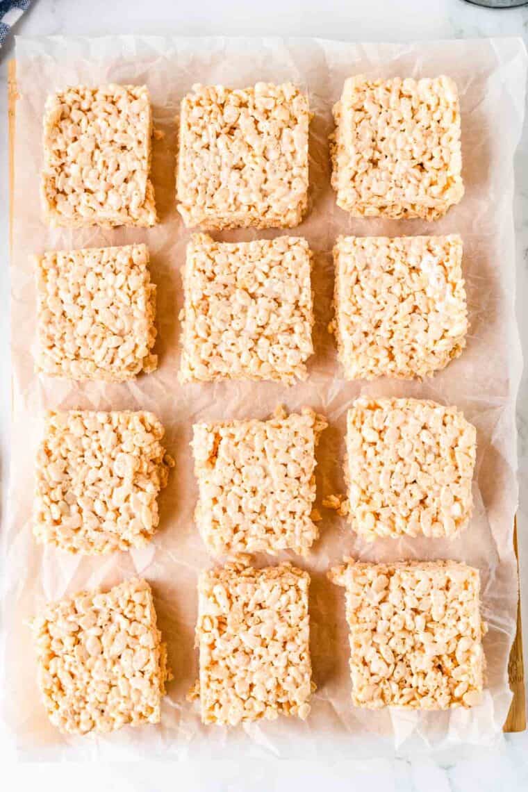 Overhead image of rice krispie treats spread out on a sheet of parchment paper.
