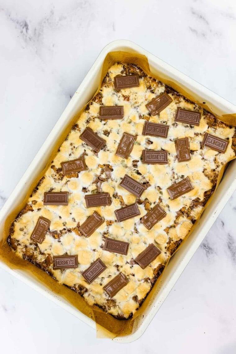 Scattering Hershey's chocolate pieces over s'mores bars.
