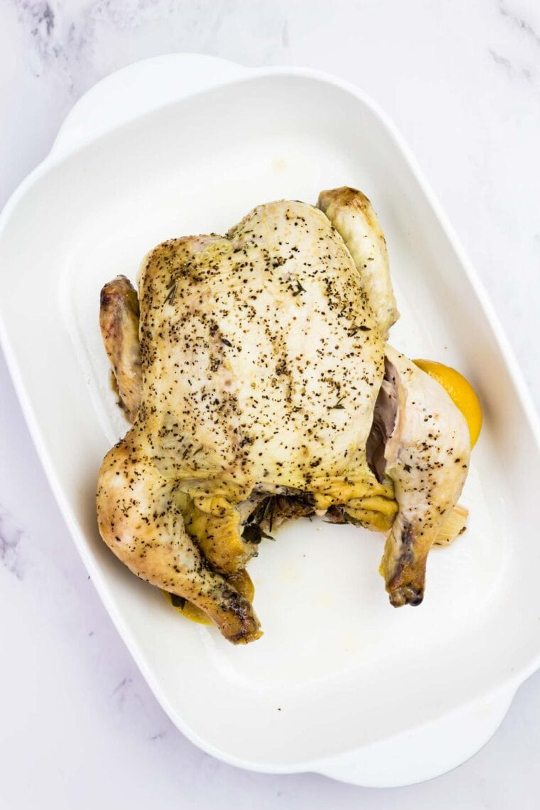 Lemon roast chicken resting in a casserole dish.