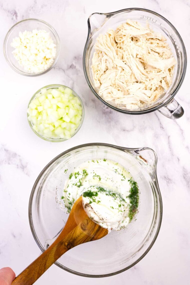 This Greek-ish tzatziki chicken salad combines juicy chicken, crunchy cucumber, and tangy Greek yogurt dressing with lemon, dill, and garlic. Mixing together the ingredients for Geek yogurt chicken salad dressing.