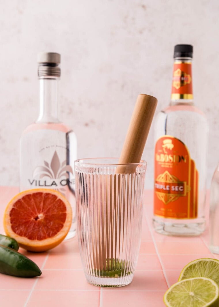 Muddling jalapeno in a cocktail shaker.