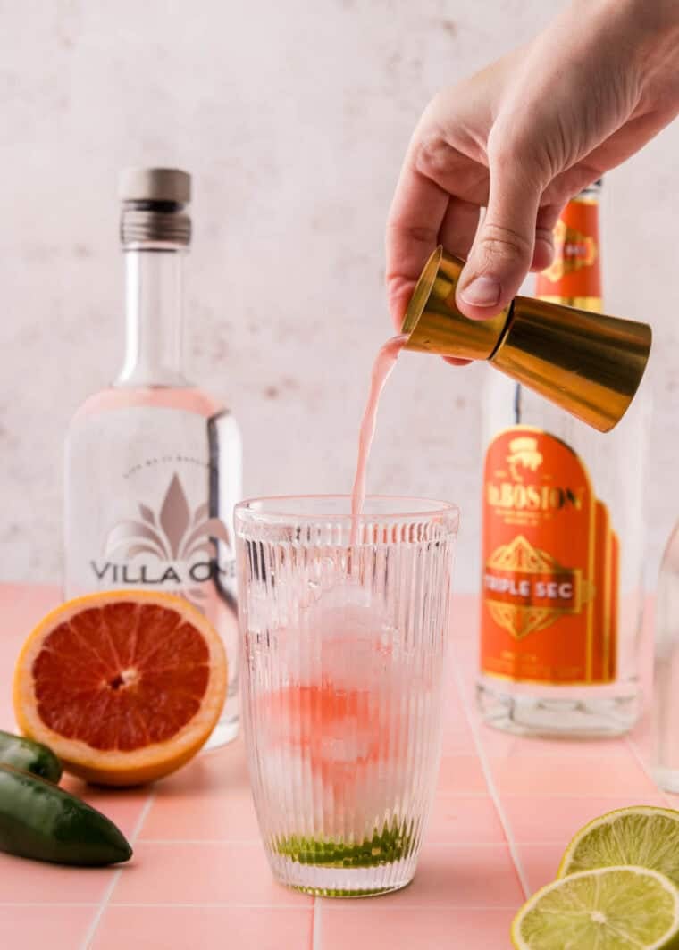 Adding grapefruit juice to a cocktail shaker.