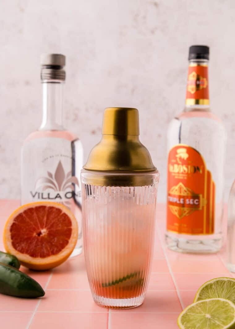 A cocktail shaker full of ingredients for a grapefruit margarita.