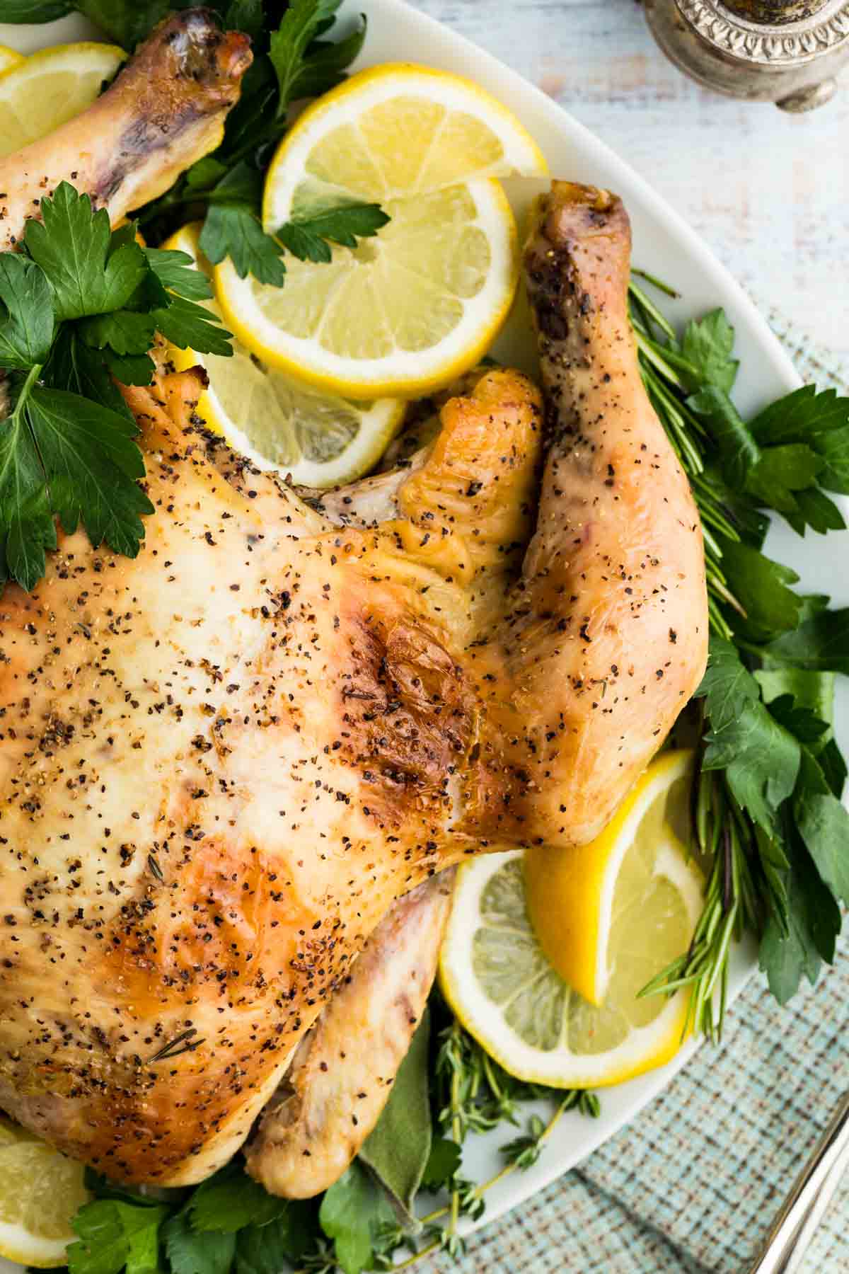 Overhead image of a whole lemon-roasted chicken on a serving plate.