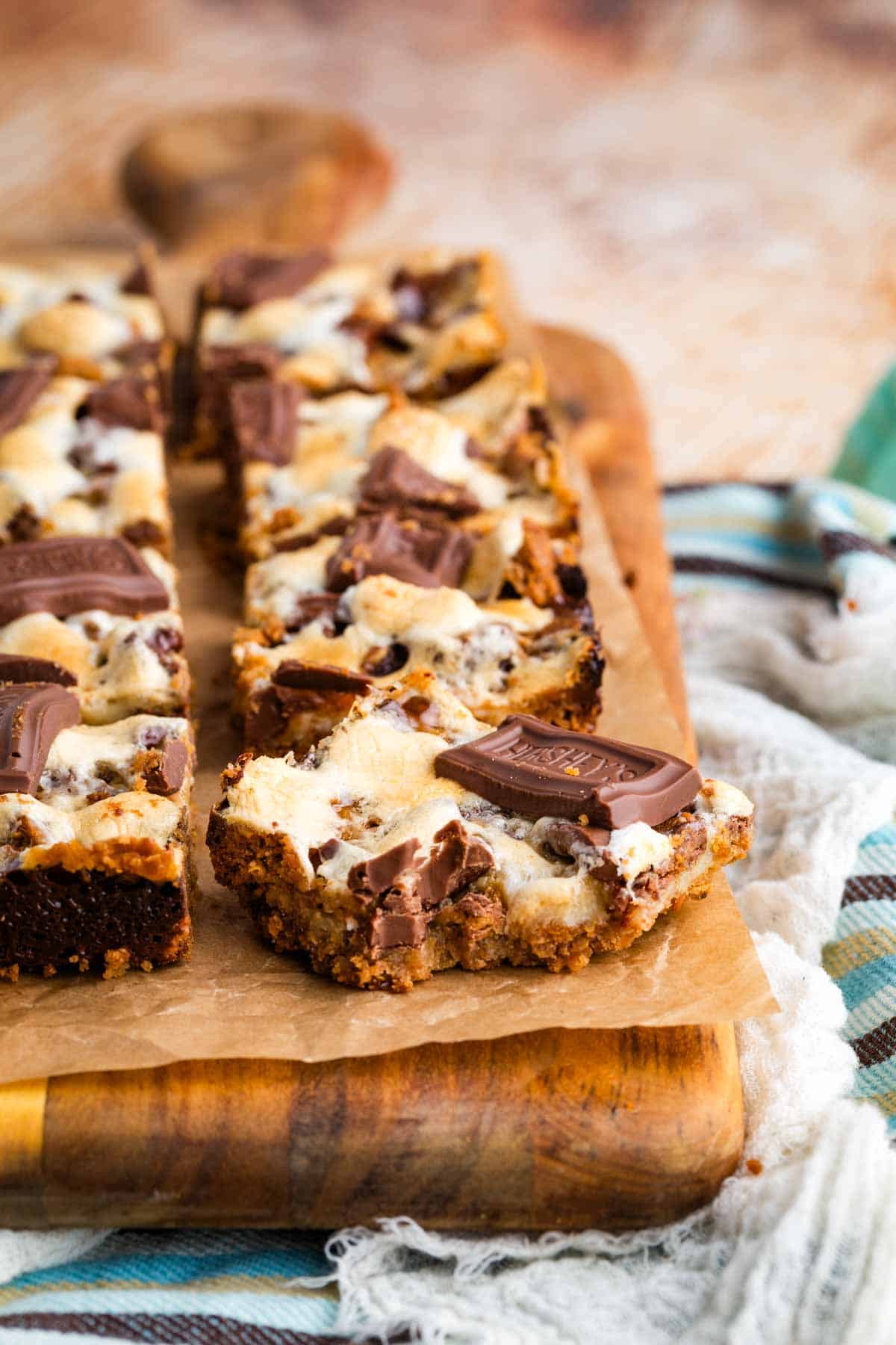 S'more bars on a cutting board. One has a bite taken out of it.
