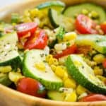 Zucchini, corn, and tomatoes in a wooden bowl with text overlay that says "Sauteed Summer Vegetables".